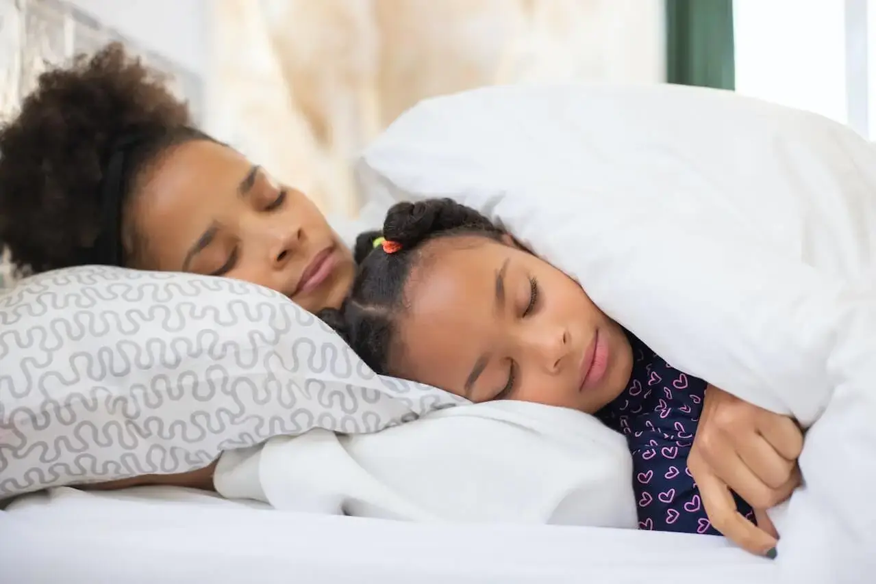 Mujer y niña durmiendo en una cama